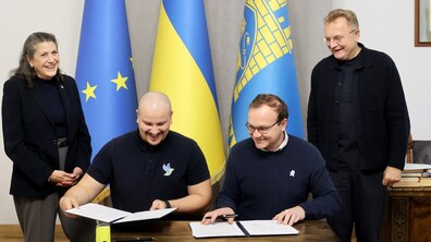 Перший заступник міського голови Львова Андрій Москаленко та представник Nova Ukraine Гліб Антонов підписують меморандум про співпрацю. Позаду стоять генеральна директорка Nova Ukraine Ерін Маккі та міський голова Львова Андрій Садовий