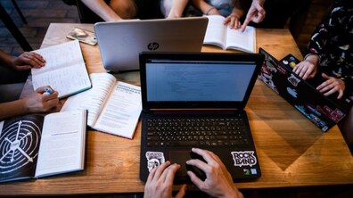 Люди сидять за комп’ютерами та записують щось в блокнотах. Фото ілюстративне.