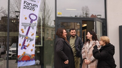 Молоді люди спілкуються біля входу. Поруч банер на якому пише Forum 2025.
