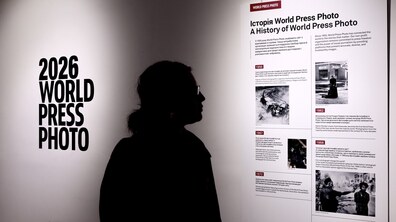 На тлі білої виставкової стіни з написом «World Press Photo» - чіткий темний силует відвідувача. Людина в профіль уважно розглядає інформаційний стенд, де висвітлено хронологічну історію міжнародного конкурсу з архівними фотографіями.