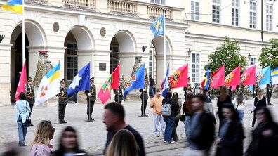 Урочиста церемонія винесення прапорів військових та оборонних структур: на площі Ринок перед будівлею міської Ратуші розміщені великі прапори, біля яких стоять курсанти; на передньому плані видно людей, які стоять та проходять повз.