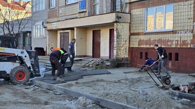 ремонтна бригада облаштовує новий тротуар і дорогу біля входу до будинку на вул. Сихівська, 1.