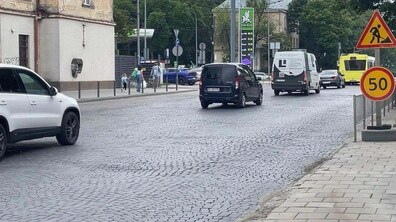 Вул. Личаківська. Дорогою рухаються кілька автомобілів і автобус, а праворуч встановлені тимчасові дорожні знаки: обмеження швидкості до 50 км/год та попередження про дорожні роботи. Уздовж дороги прокладений тротуар, а на задньому плані видно будівлі, дерева, автозаправку та трамвай.