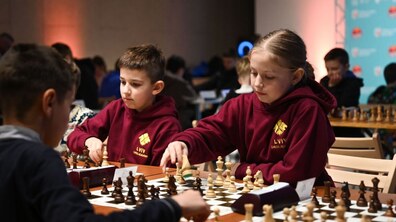 Учні грають у шахи за довгими столами у просторій залі під час міського етапу спортивної шкільної ліги у Львові