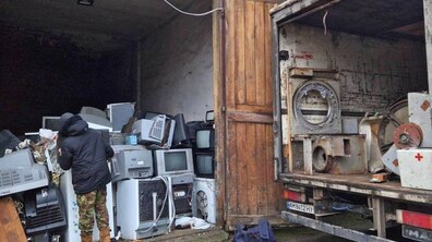 Працівник комунального підприємства оглядає великогабаритне сміття. Поруч видно частину вантажного авто.