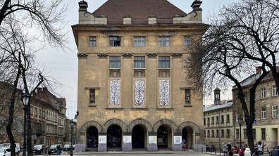 Будинок театру ляльок жовтого кольору з коричневим дахом. Перед будинком вздовж алеї висаджені дерева.