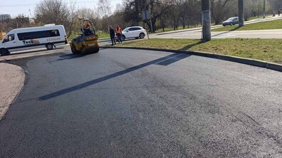 Каток вирівнює новий шар асфальту. Поруч працюють робітники та їздять транспортні засоби. Фото ілюстративне.
