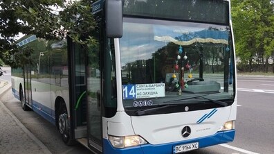 Великий біло-синій автобус на одній з вулиць Львова. Навколо видно зелені дерева