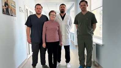 Пацієнтка Галина та лікарі, які її оперували – хірург Ярослав Вовчанський, хірург-онколог Володимир Дорожинський та хірург Андрій Вербовецький стоять у коридорі лікарні святого Пантелеймона; всі усміхнені.