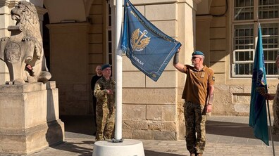 урочиста церемонія підняття прапора Морської піхоти України біля будівлі міської ратуші. Двоє представників морської піхоти у військовій формі тримають прапор