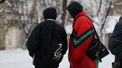 Двоє чоловіків стоять на вулиці та дивляться вдалечінь, навколо сніг